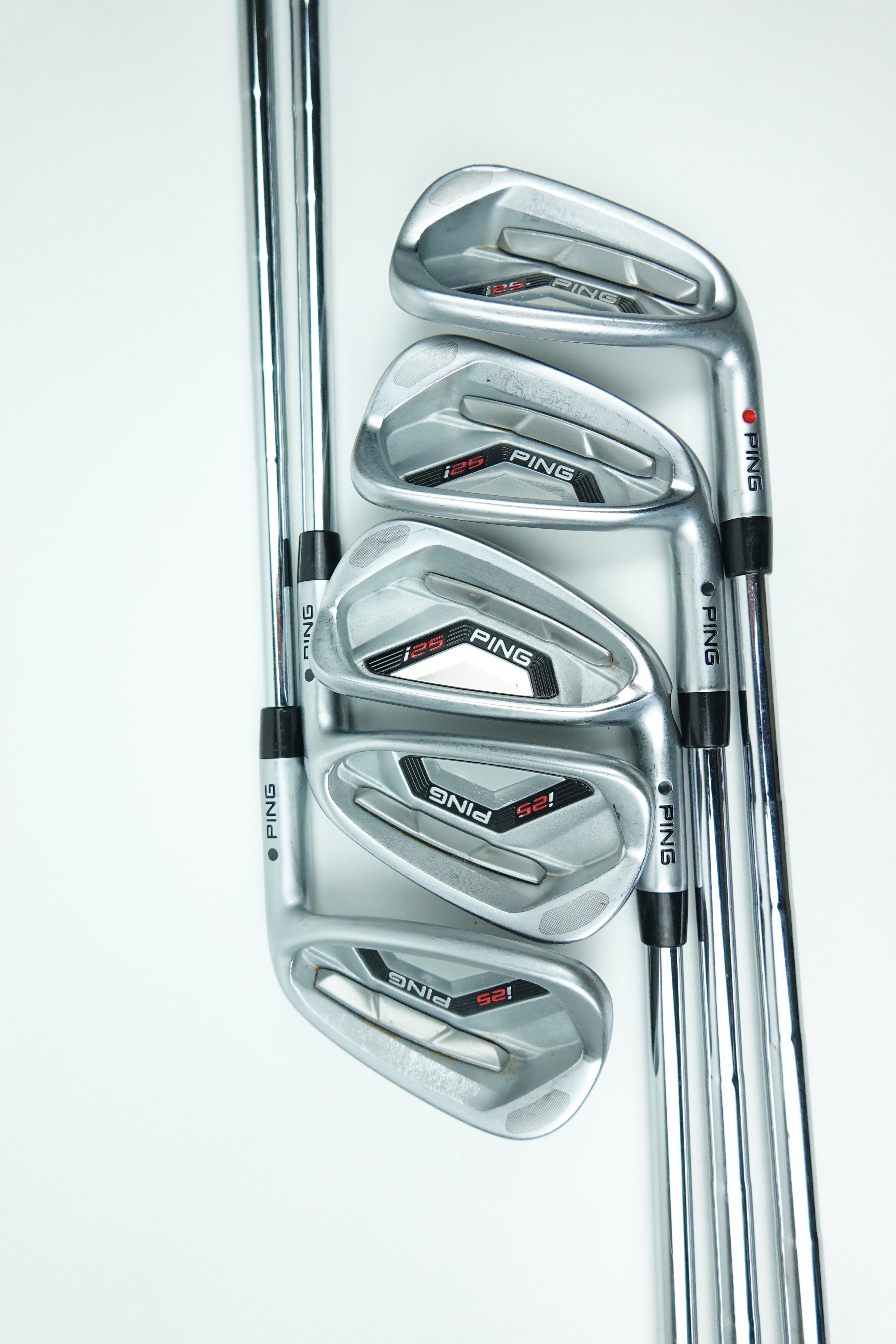 Five PING iron golf clubs arranged in a fan shape on a clean white background, showing the clubheads and part of the shafts.