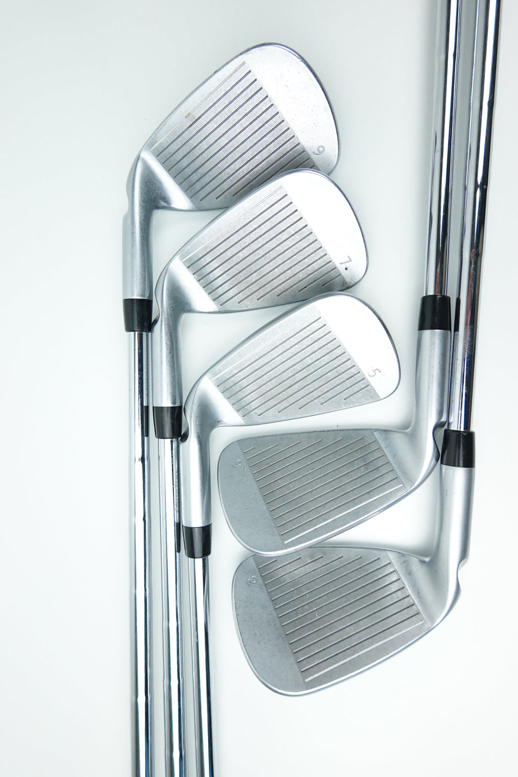Four silver metal golf iron clubs arranged overlapping on a clean white background.