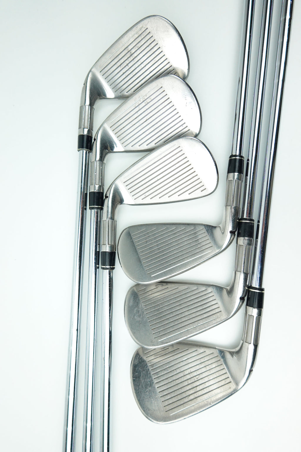 A set of five silver metal golf iron clubs arranged in a fan shape on a clean white background.
