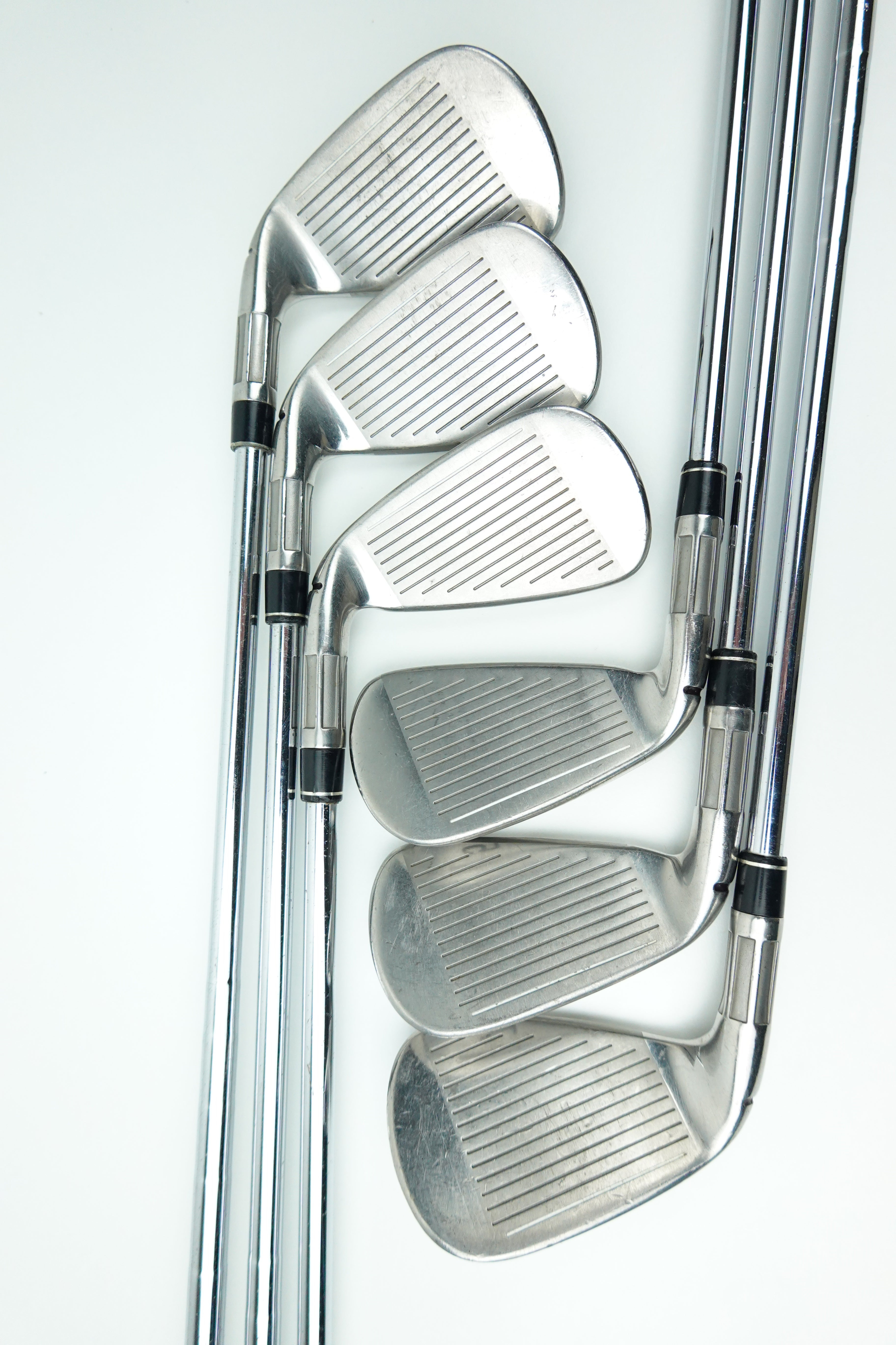 A set of five silver metal golf iron clubs arranged in a fan shape on a clean white background.