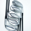 Four golf iron clubs with polished silver metal heads and black shafts, arranged diagonally on a clean white background.