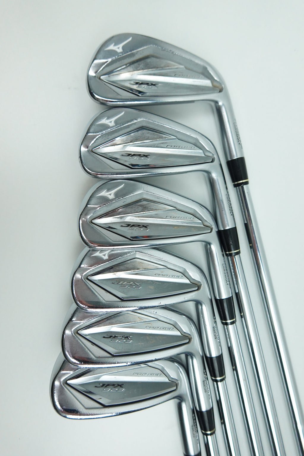 A set of seven polished steel golf irons arranged in a fan shape on a clean white background.