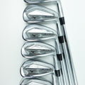 Six Mizuno golf iron clubs arranged in a row on a clean white background, showing their polished silver metal heads and black shaft bands.