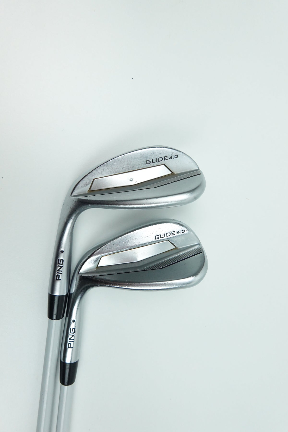 Two PING golf wedges with metallic silver and black clubs, positioned diagonally on a clean white background.