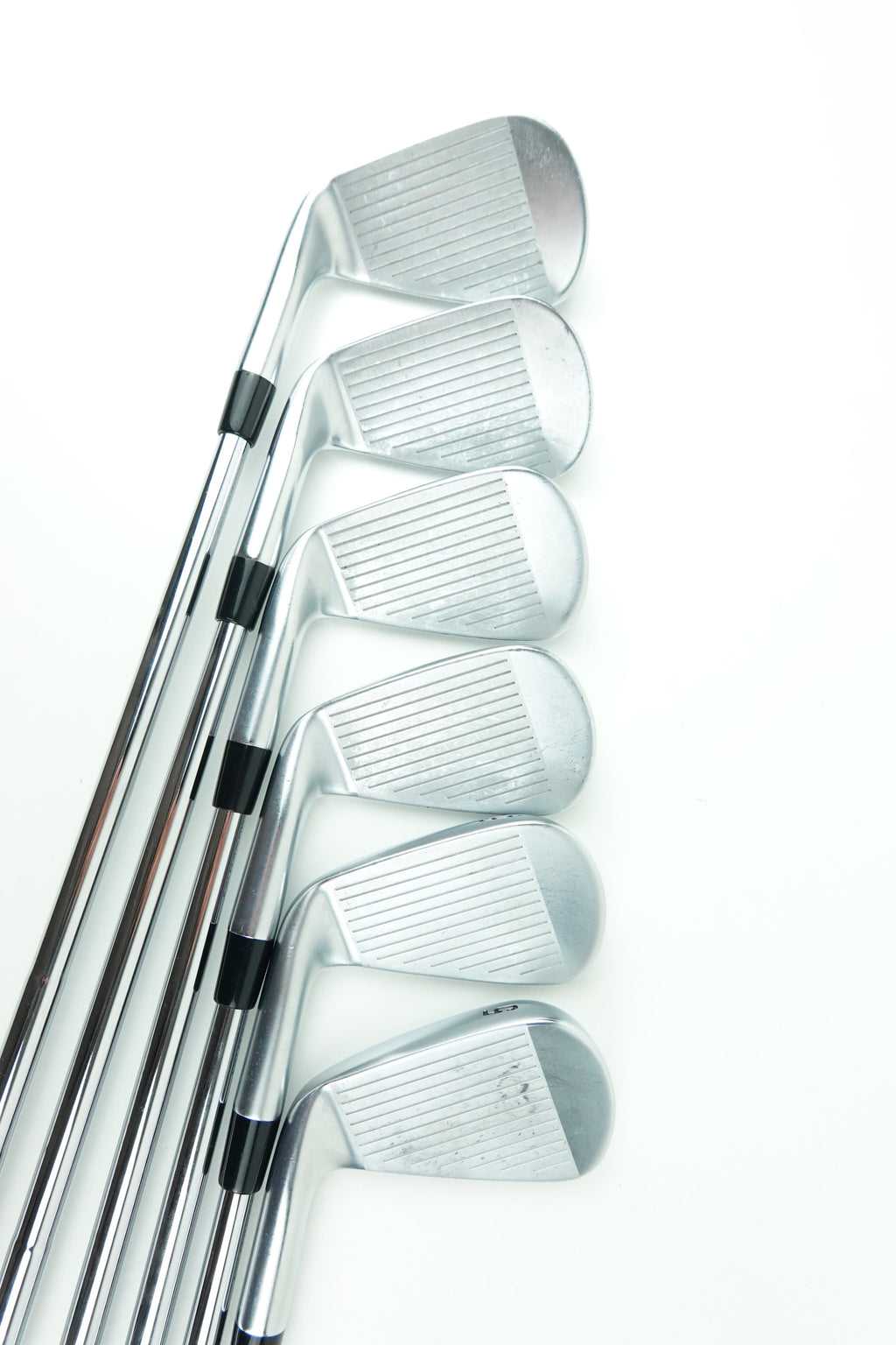 Six silver metal golf iron clubs arranged in a fan shape on a plain white background.