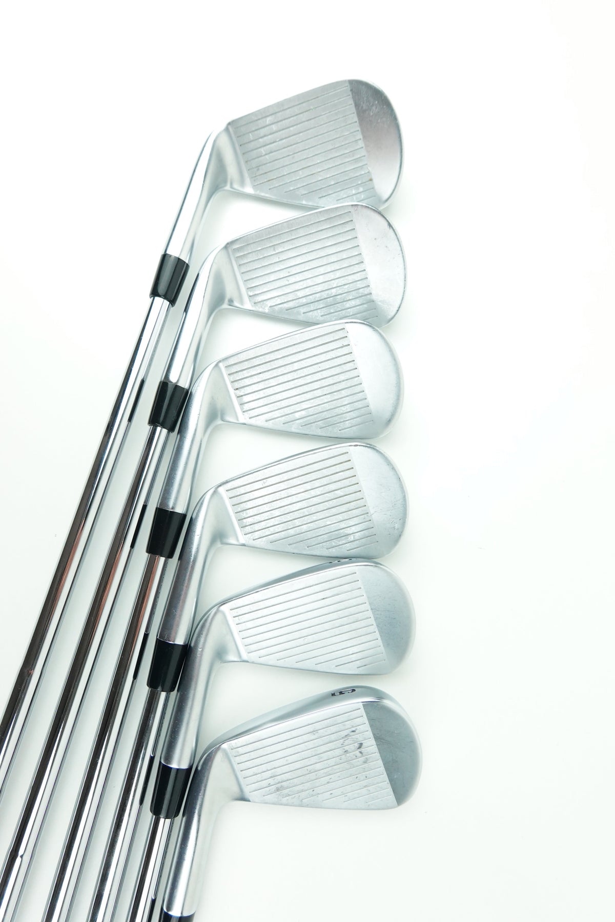 Six silver metal golf iron clubs arranged in a fan shape on a plain white background.